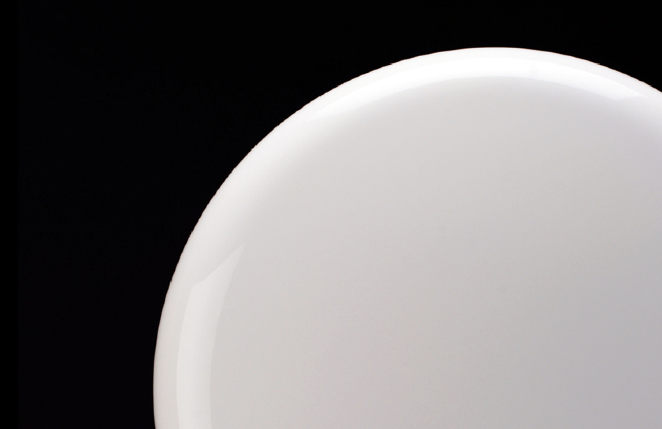 Close-up of the smooth white curved surface of a paper dispenser against black