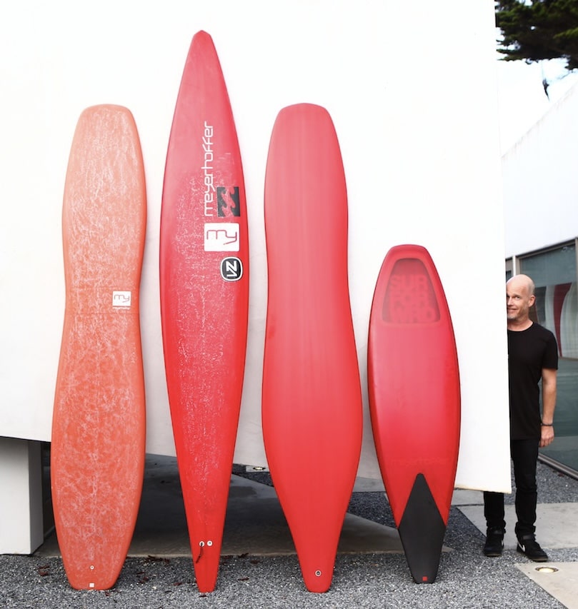 Four red and orange Meyerhoffer surfboards standing side by side